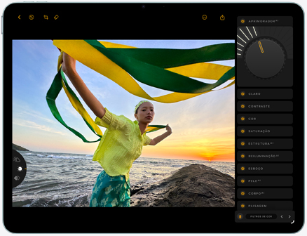 Parte da frente do iPad Air mostrando a edição da foto de uma pessoa segurando um tecido verde e amarelo contra o pôr do sol na praia, com as ferramentas de edição visíveis no lado direito