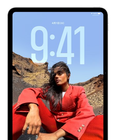 iPadのロック画面。座っている人物の写真の後ろに時刻を示す数字が大きく表示されている
