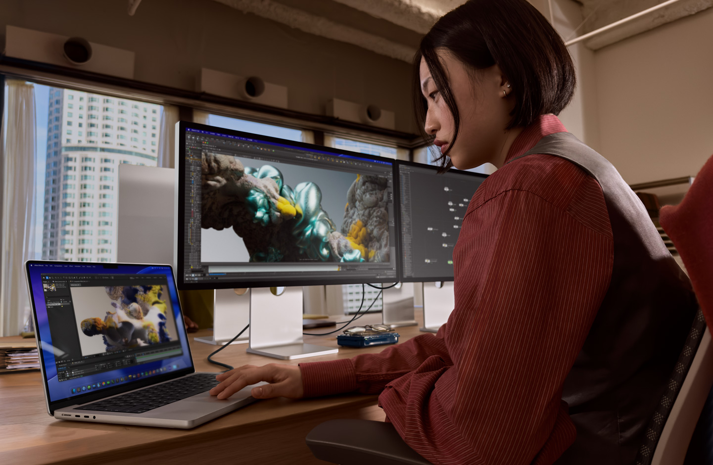 オフィスでMacBookノートブックを使って作業している人物。Thunderbolt 5ポートでStudio Display XDRに接続している