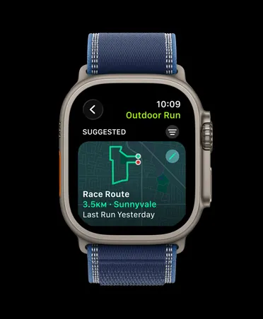 Apple Watch Ultra 3，採用原色鈦金屬錶殼，配以藍色配亮藍色越野手環；螢幕顯示户外跑步體能訓練的路線競速功能