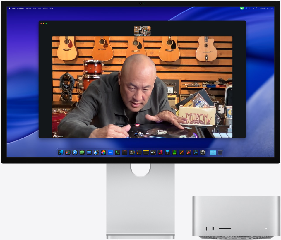 While on a video call on Studio Display XDR with Mac Studio tucked underneath, a person at a music store looks closely at a turntable